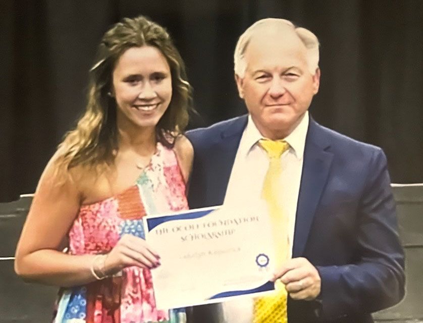 A man and a woman are posing for a picture and the woman is holding a certificate