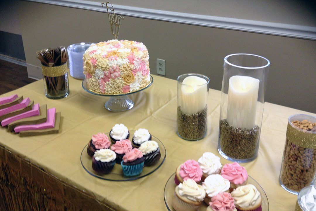 Table with a decorated cake, cupcakes, candles, and snacks.