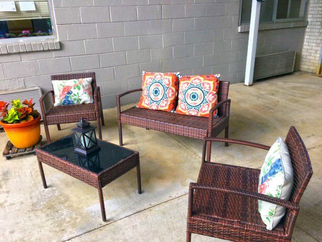 Outdoor patio set with wicker furniture, colorful pillows, and a small table.