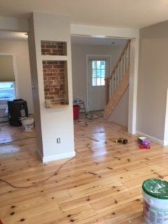 A living room with wooden floors and a bucket of paint