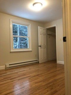 An empty bedroom with hardwood floors and a window.