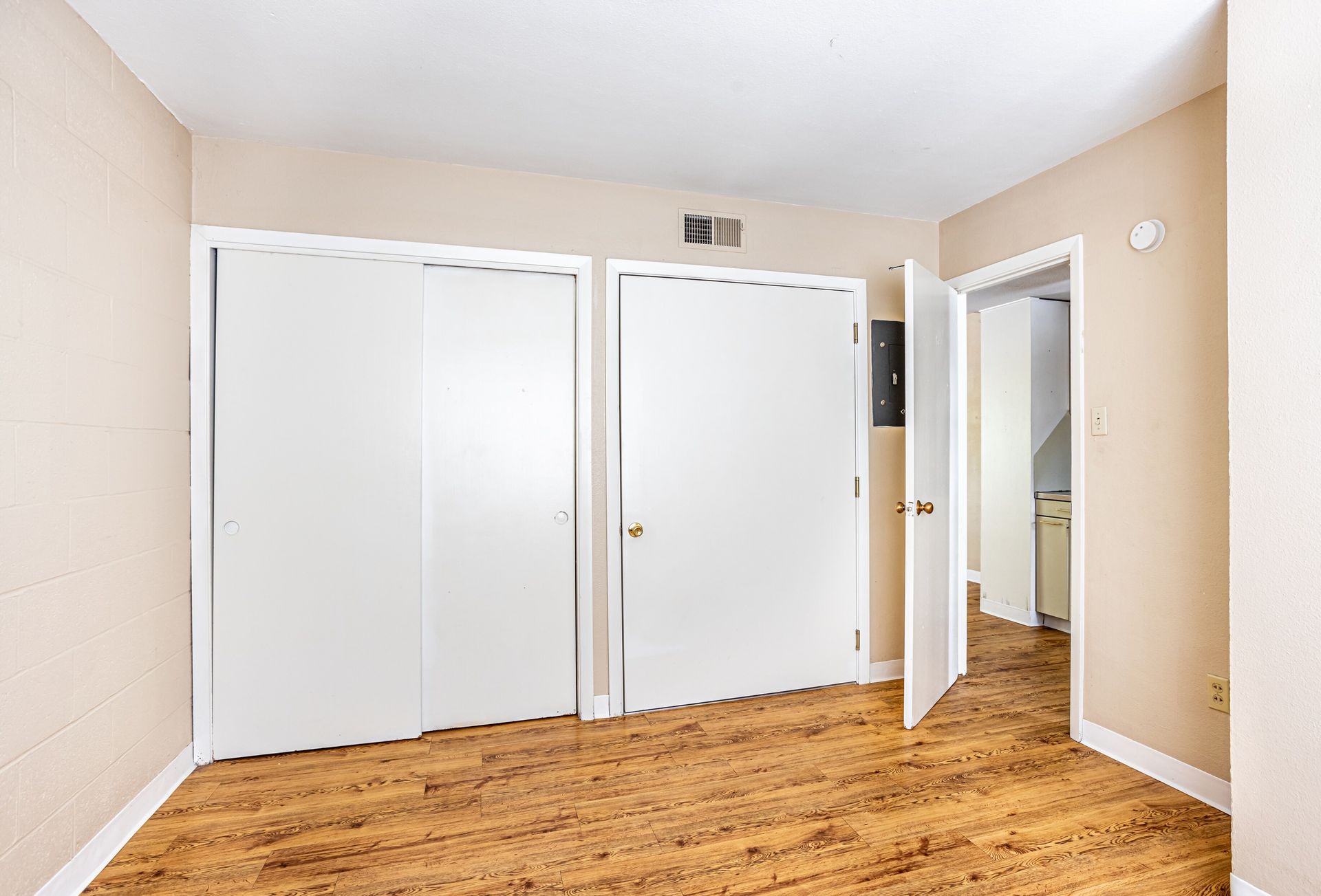 Empty room with white closet doors and a partially open doorway, carpeted floors.
