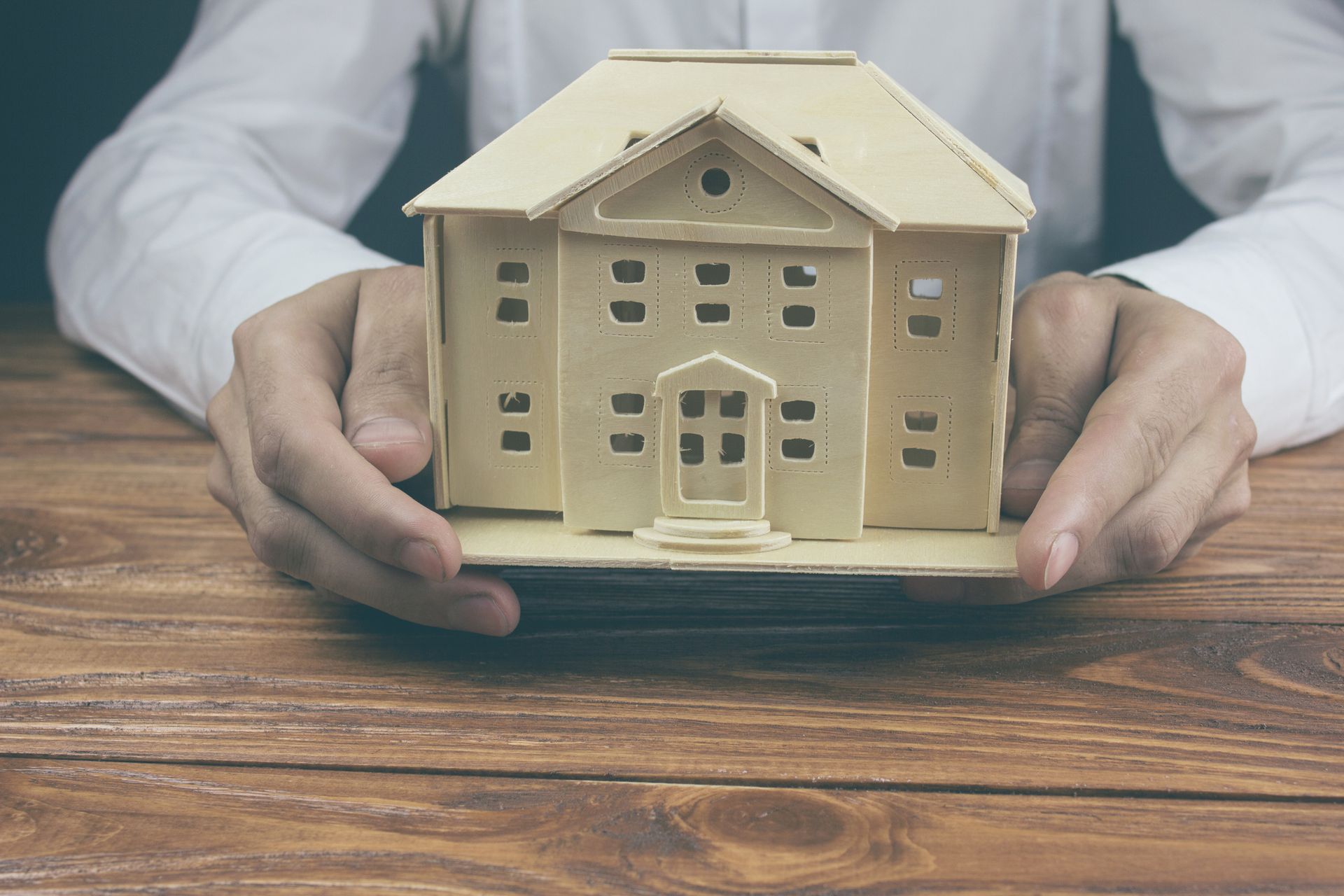 A person is holding a model house in their hands – Panama City, FL – Harry Grizzle Insurance