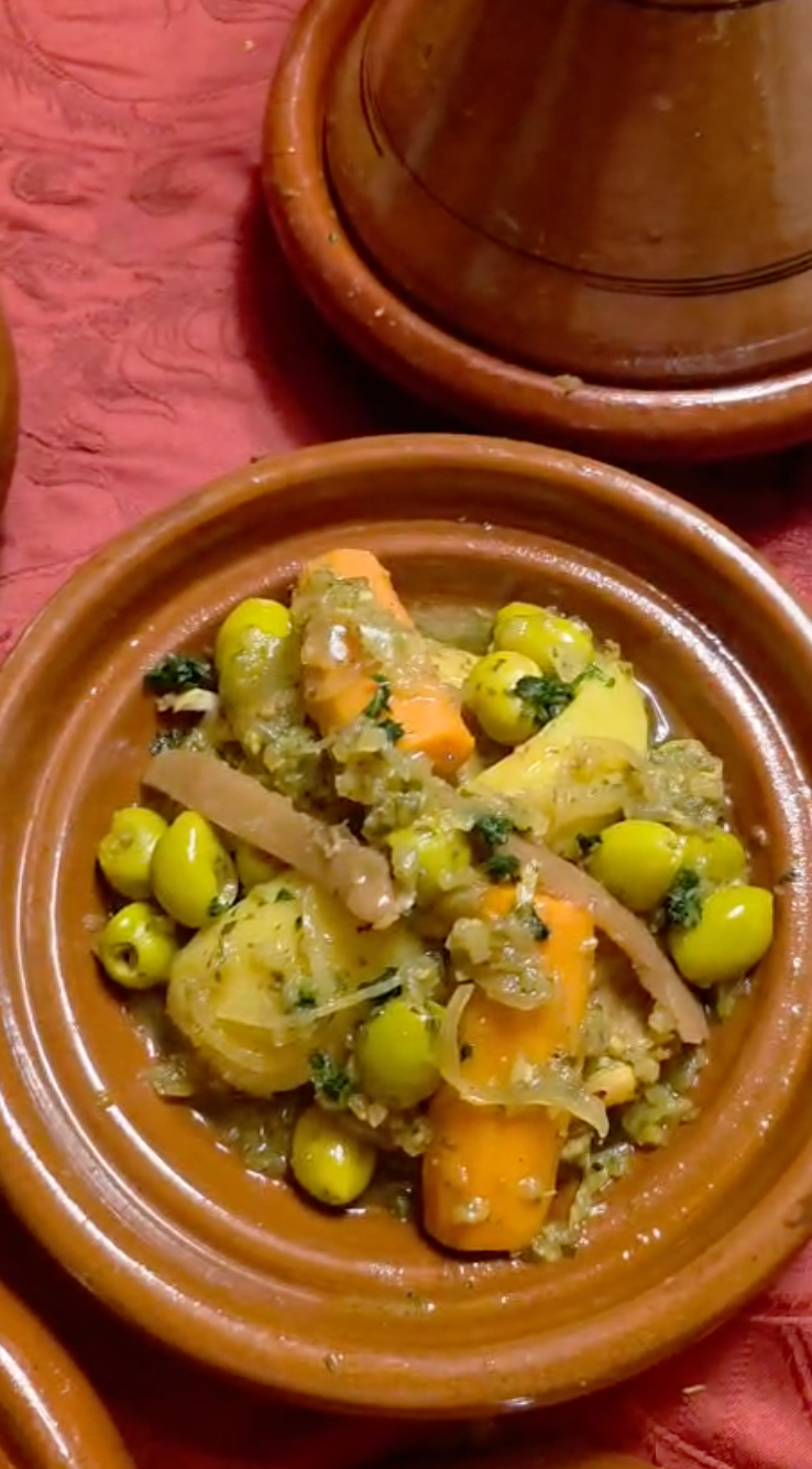 Tajine de légumes marocain aux carottes, olives et herbes aromatiques, cuit dans un pot en terre cuite.