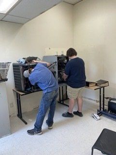 Two men are working on a computer in a room
