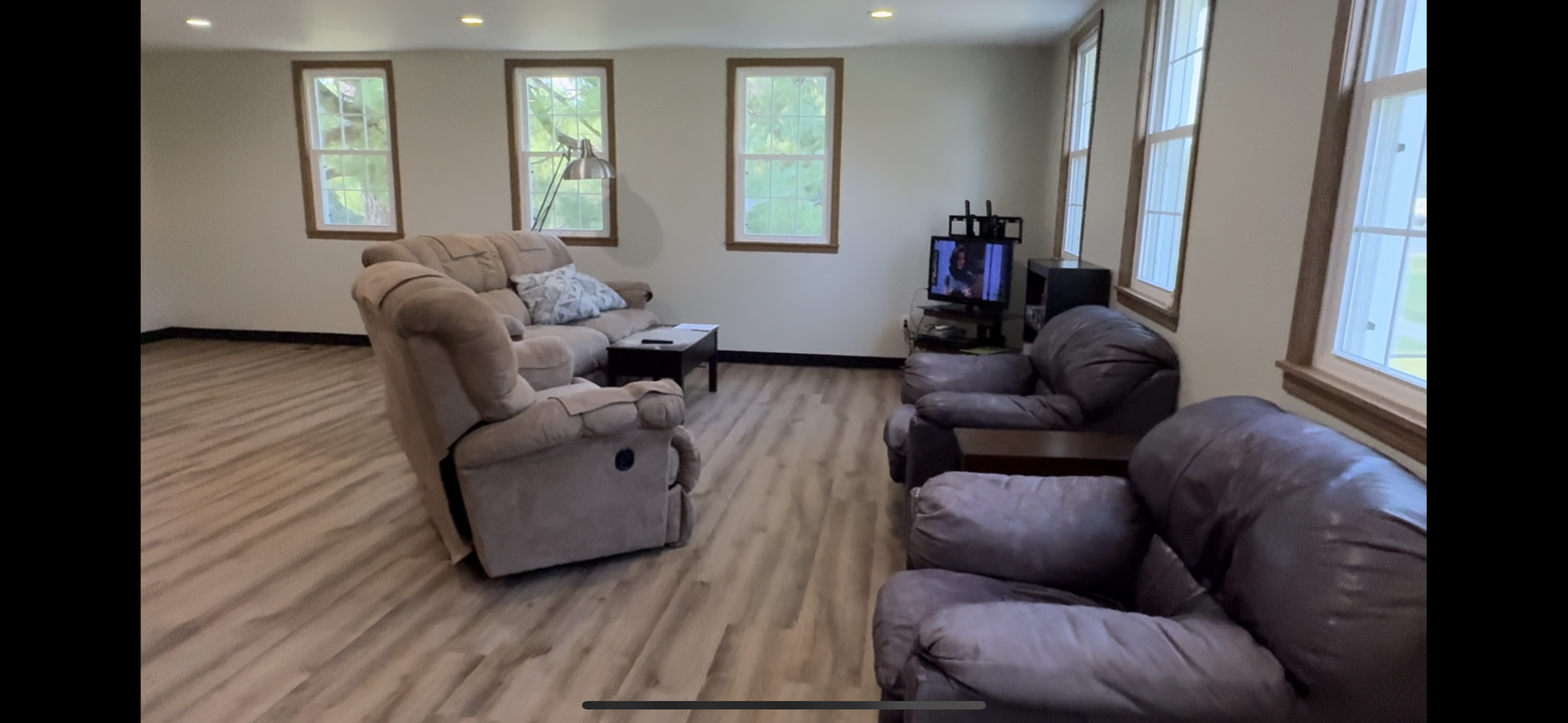 A living room with a couch , chairs , and a television.