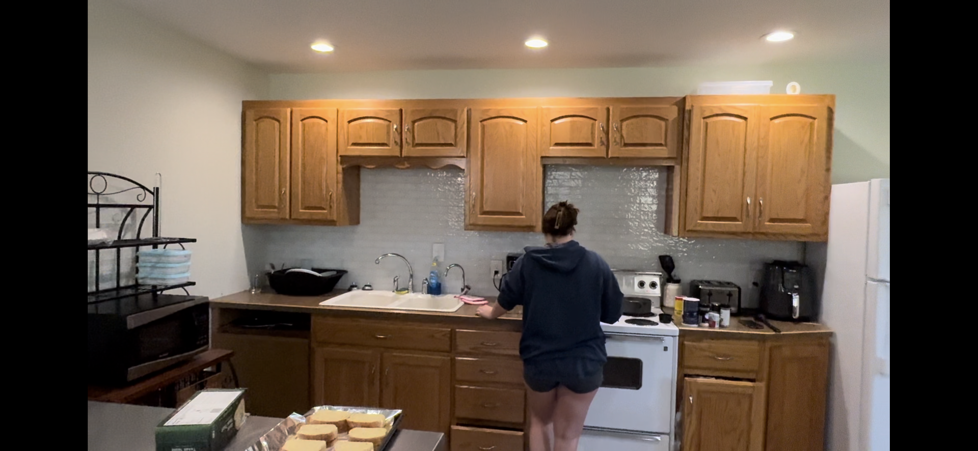 A woman is standing in a kitchen preparing food.