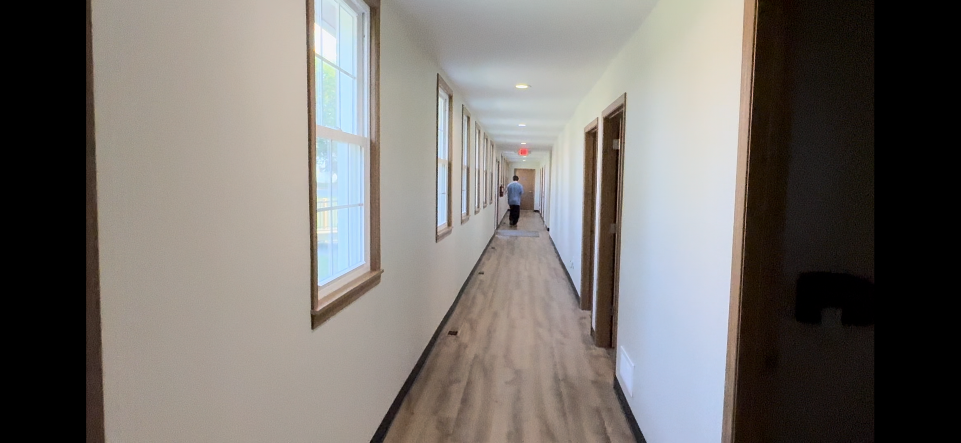A long hallway with a lot of windows and a person walking down it.
