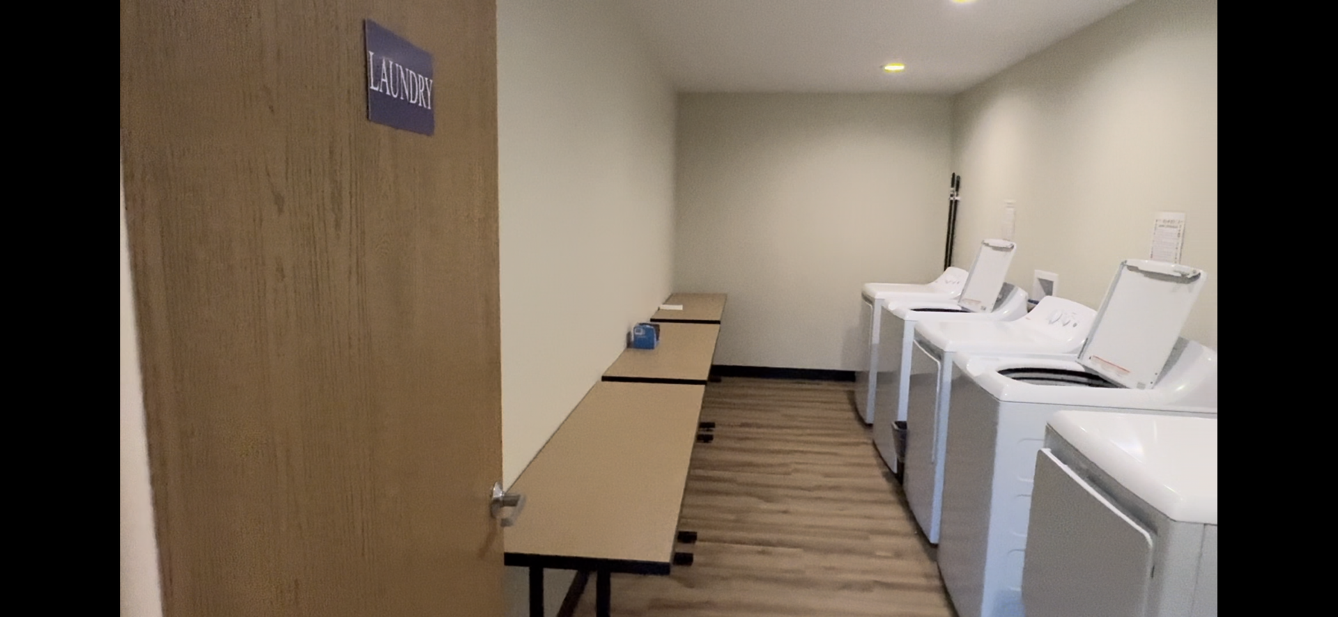 A laundry room with a row of washing machines and dryers.