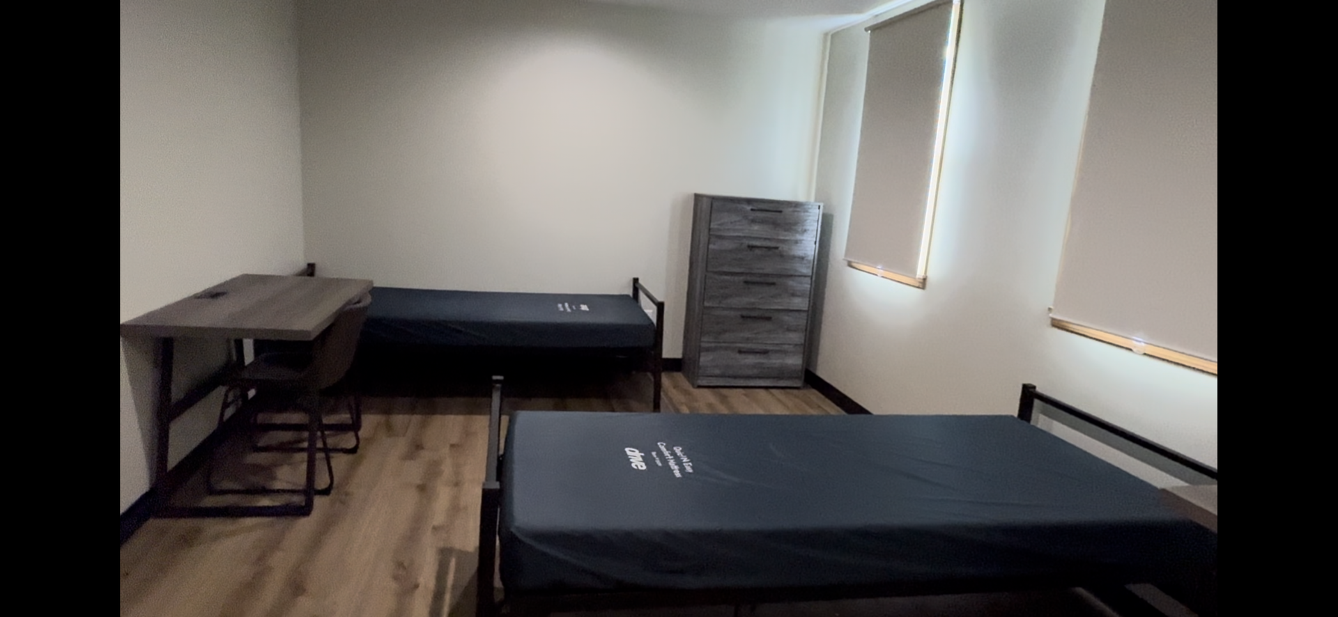 A room with two beds and a desk in it.