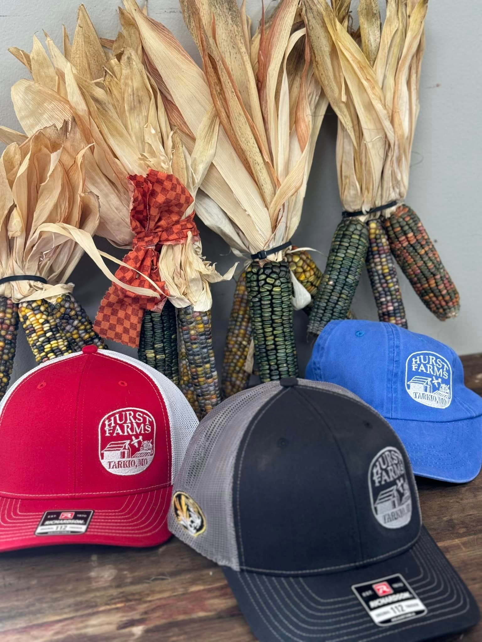 A group of hats sitting on top of a wooden table next to corn on the cob.