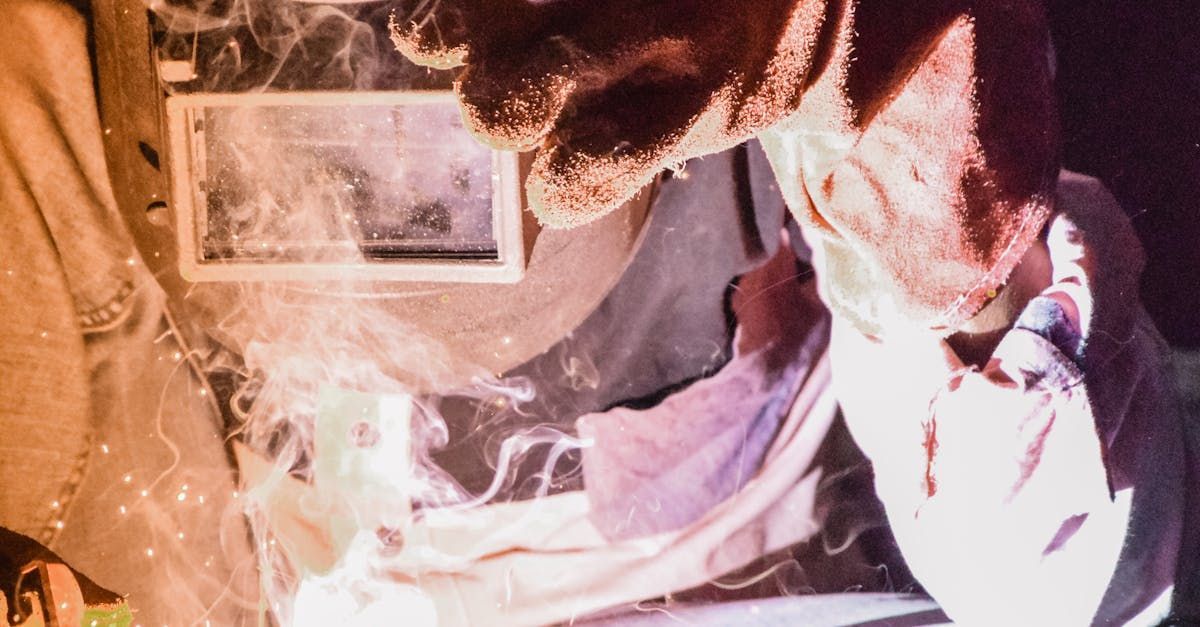 A man wearing a welding helmet is welding a piece of metal.