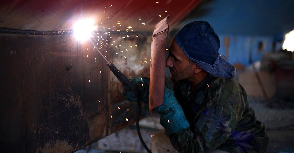A man is welding a piece of metal in a factory.