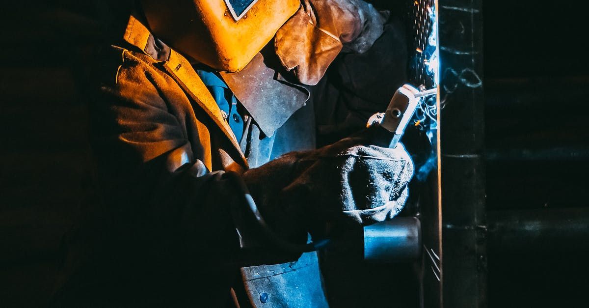 A man is welding a pipe in a dark room.