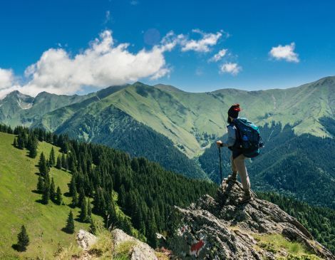 A person with a backpack is standing on top of a mountain.