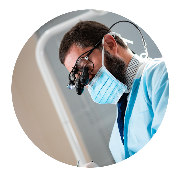 A dentist wearing a mask and magnifying glasses