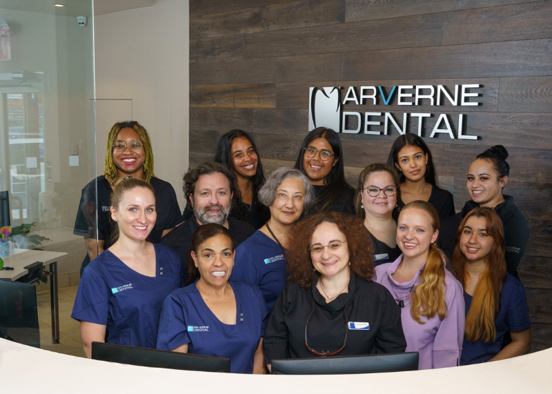 A group of people are posing for a picture in front of a dental office.