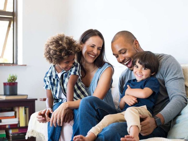 A family is sitting on a couch together and smiling.