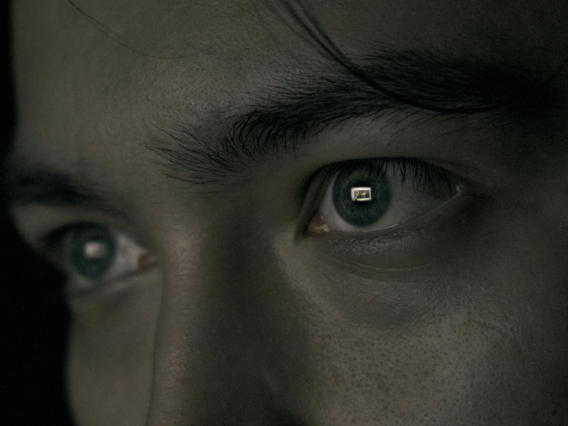 A close up of a man 's blue eye with a reflection of a phone in it.