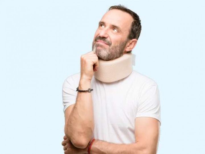 A man with a neck brace on his neck is looking up.