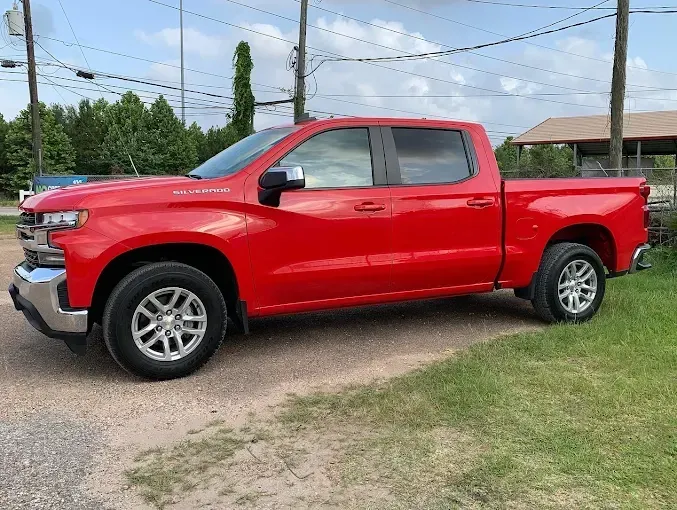 Red Chevrolet Silverado pickup truck parked on grass.