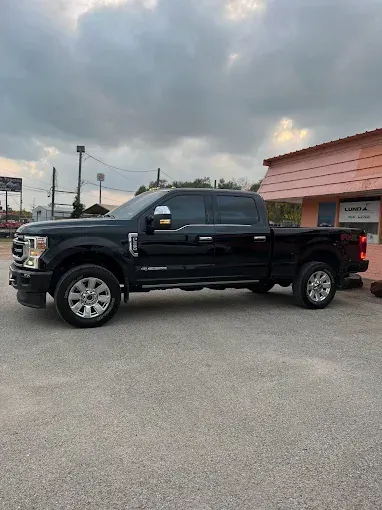 Black Ford truck parked in front of a building under a cloudy sky.