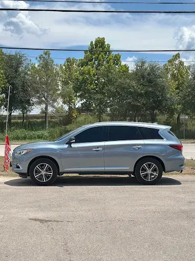 Silver SUV parked on a paved road, under a cloudy sky. Trees and power lines in the background.