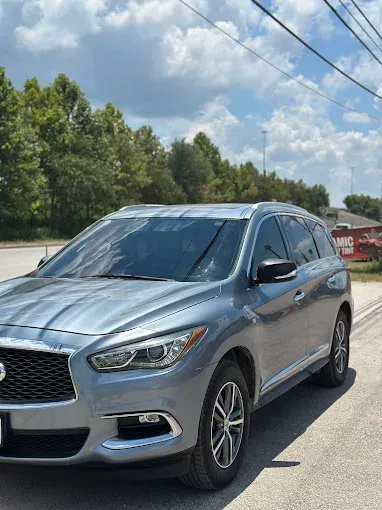 Silver Nissan SUV parked on the side of a road on a sunny day.