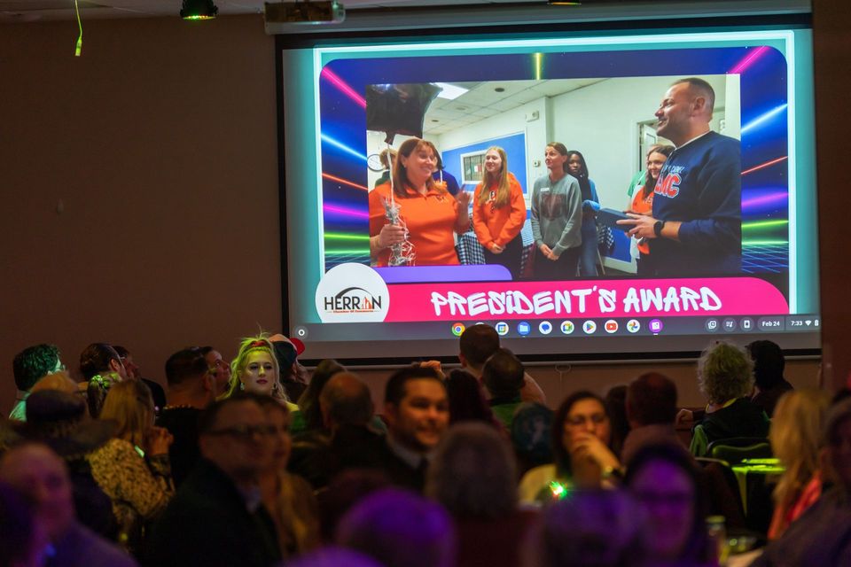 A group of people are sitting in front of a projector screen.