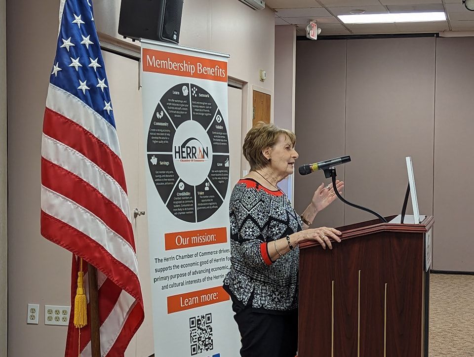 A woman is standing at a podium speaking into a microphone.