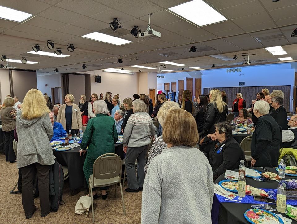 A large group of people are sitting at tables in a room.