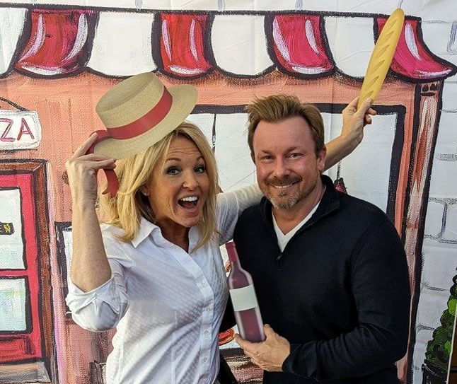 A man and a woman are posing for a picture in front of a pizza shop