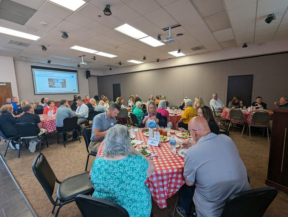 A large group of people are sitting at tables in a large room.