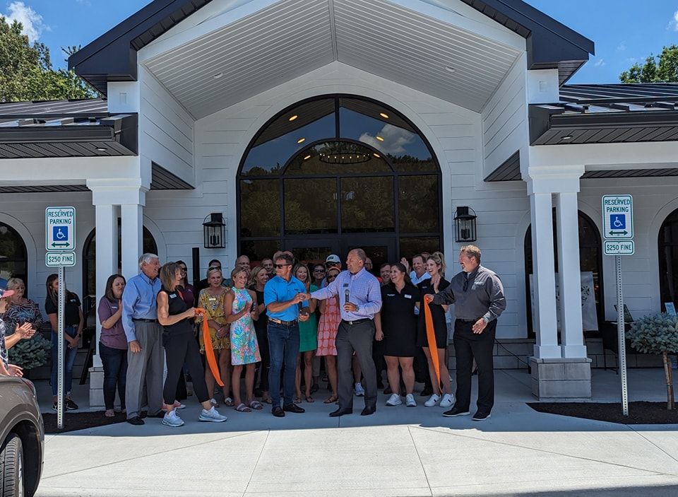 A group of people are standing in front of a building cutting a ribbon.