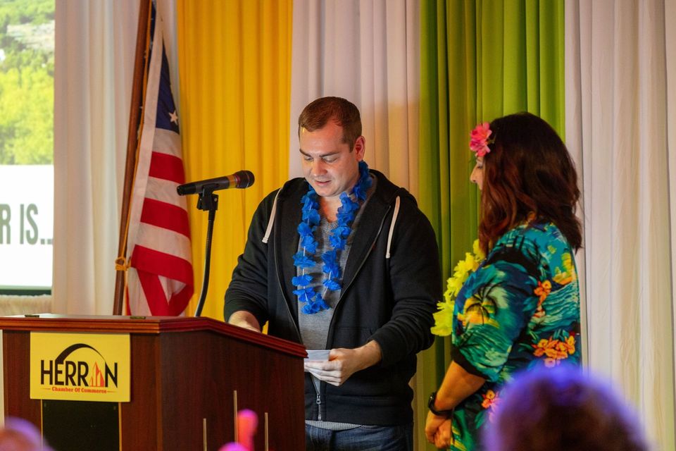 A man is giving a speech at a podium next to a woman.