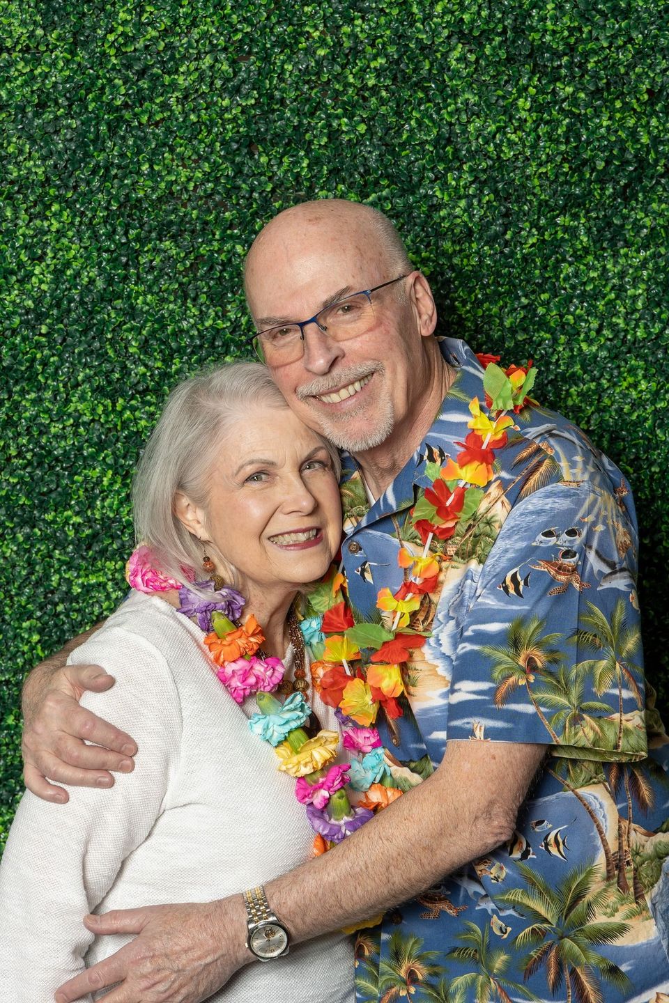 A man and a woman are posing for a picture in front of a green wall.