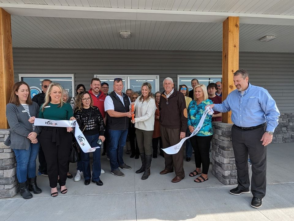 A group of people are standing in front of a building cutting a ribbon.