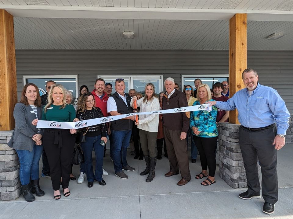 A group of people are cutting a ribbon in front of a building.