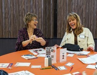 Two women are sitting at a table laughing.