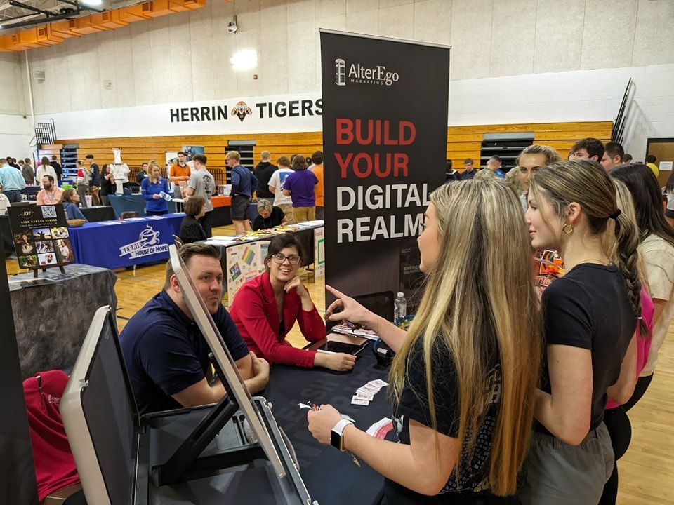 A group of people are standing around a table at a job fair.