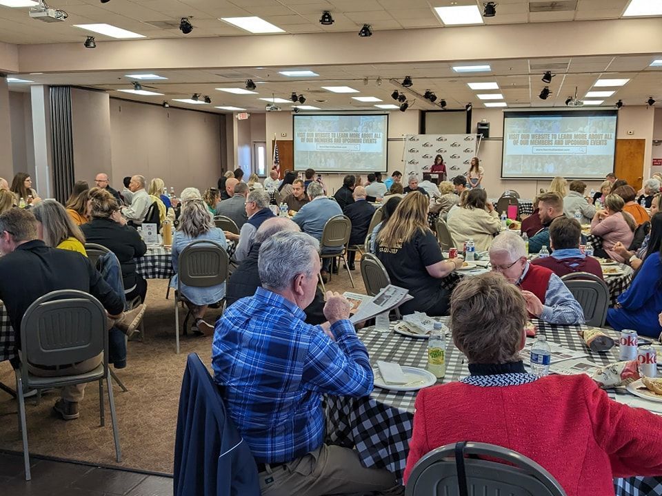 A large group of people are sitting at tables in a large room.