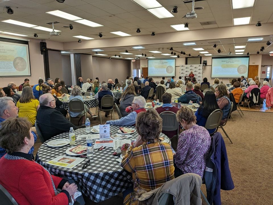 A large group of people are sitting at tables in a large room.