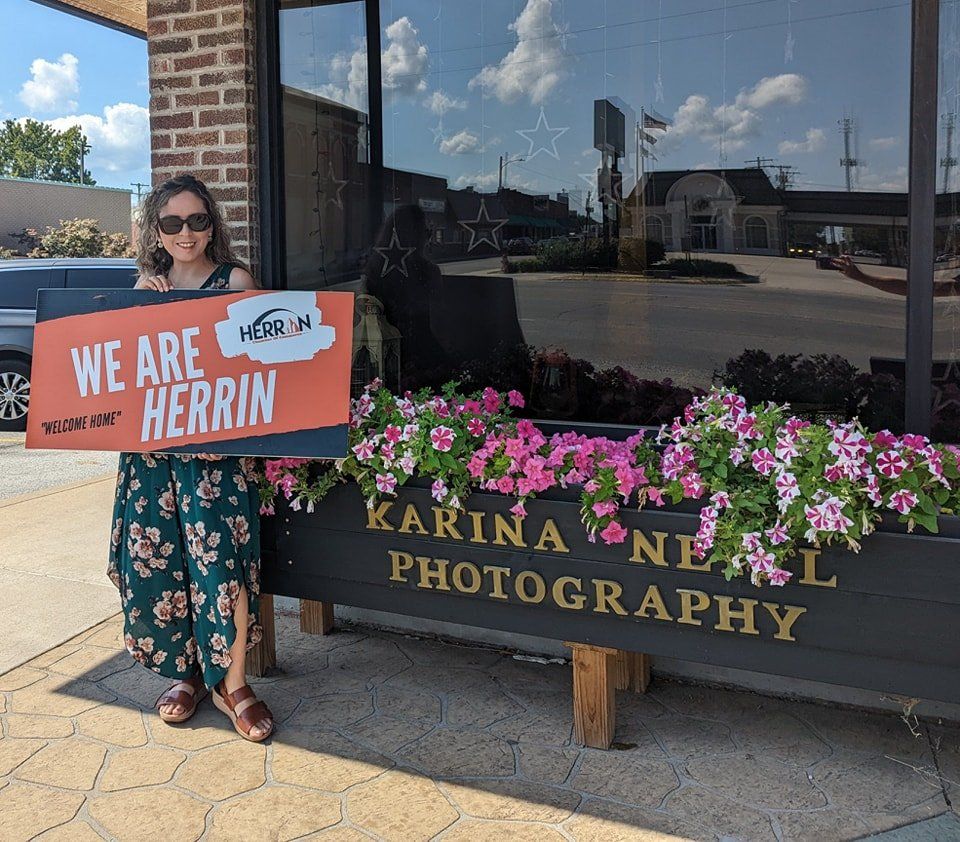 A woman holding a sign that says we are herrin