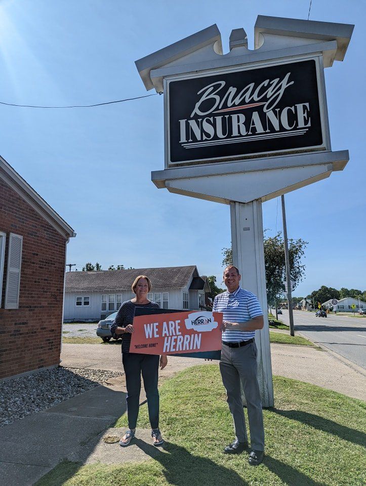 A man and a woman are standing in front of a bracy insurance sign.