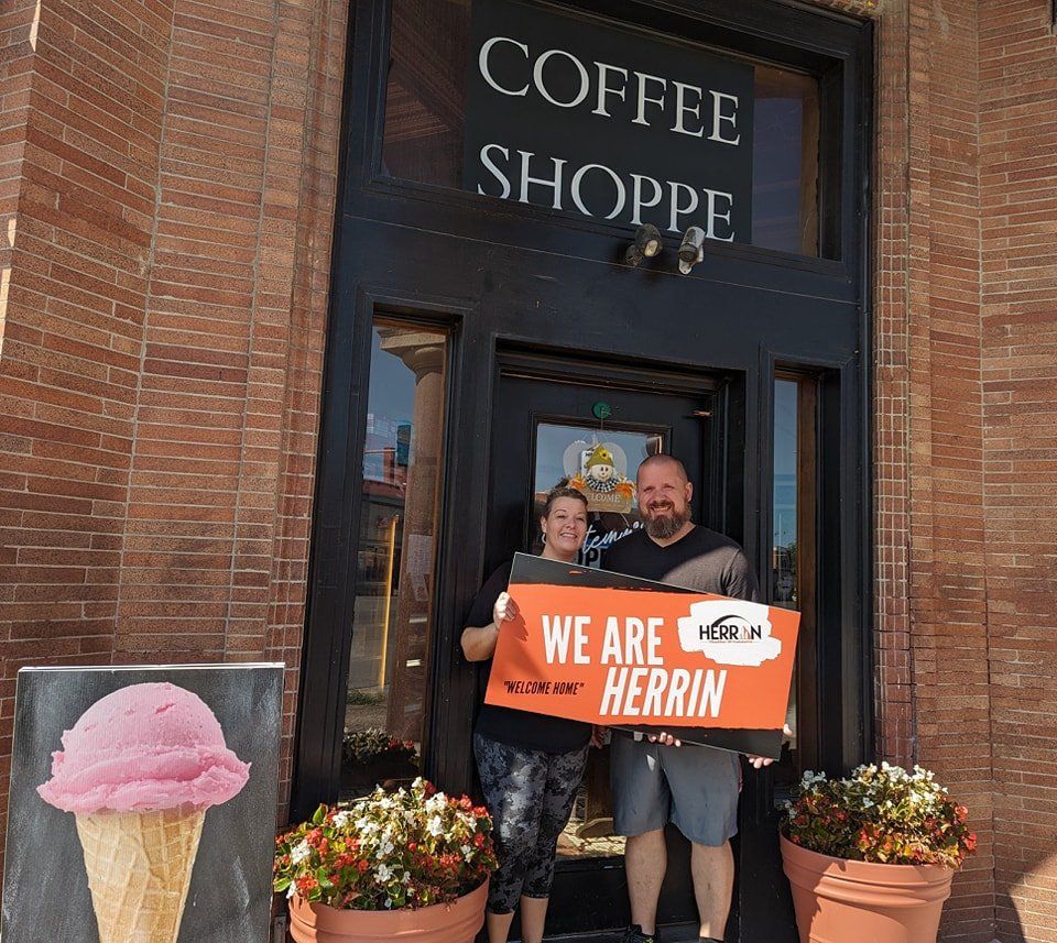 A man and woman holding a sign that says we are herrin