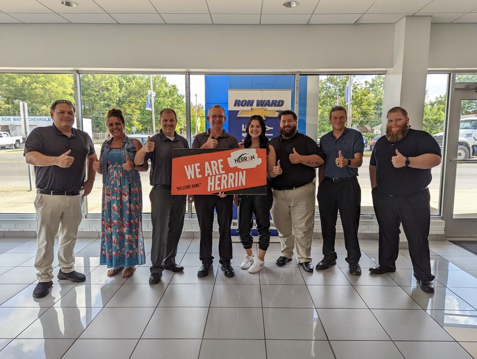 A group of people are standing in a room holding a sign that says `` we are herrin ''.