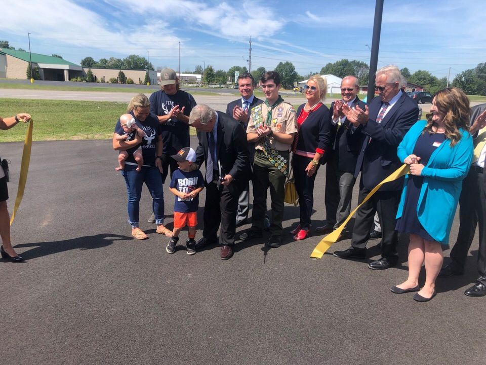 A group of people are standing around a ribbon cutting ceremony.