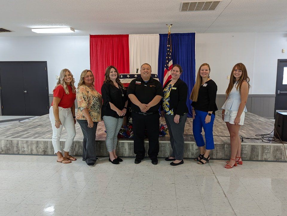 A group of people are posing for a picture in front of a flag.