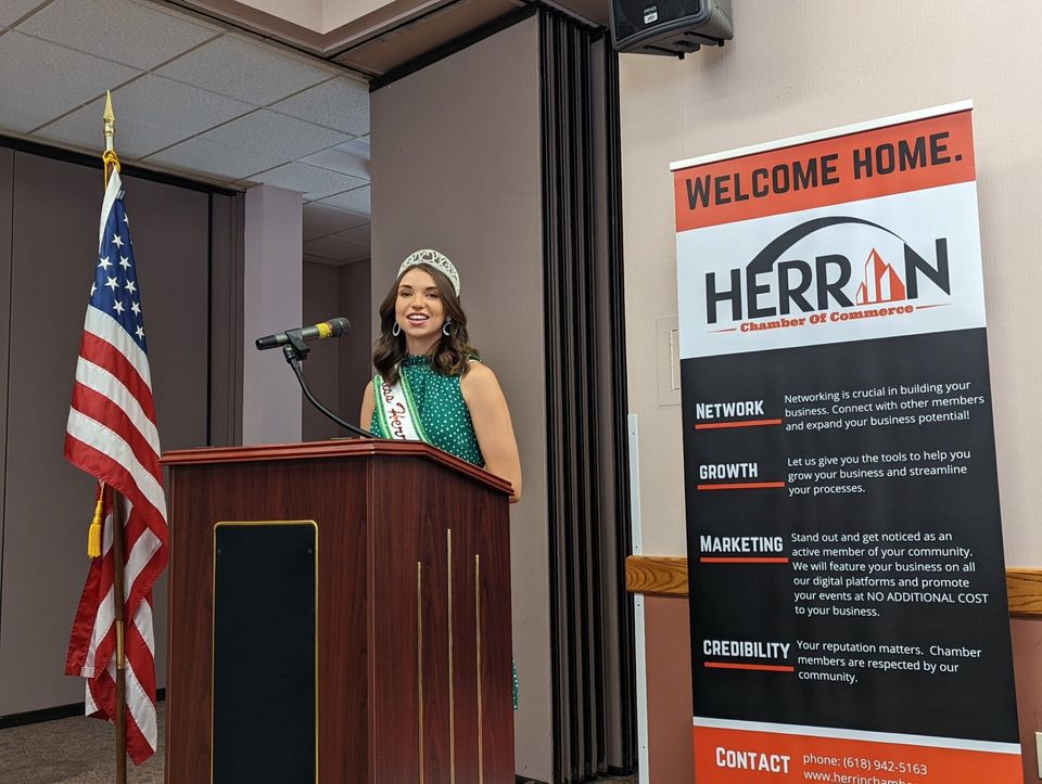 A woman is standing at a podium in front of a sign that says welcome home