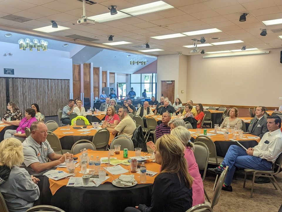 A group of people are sitting at tables in a large room.